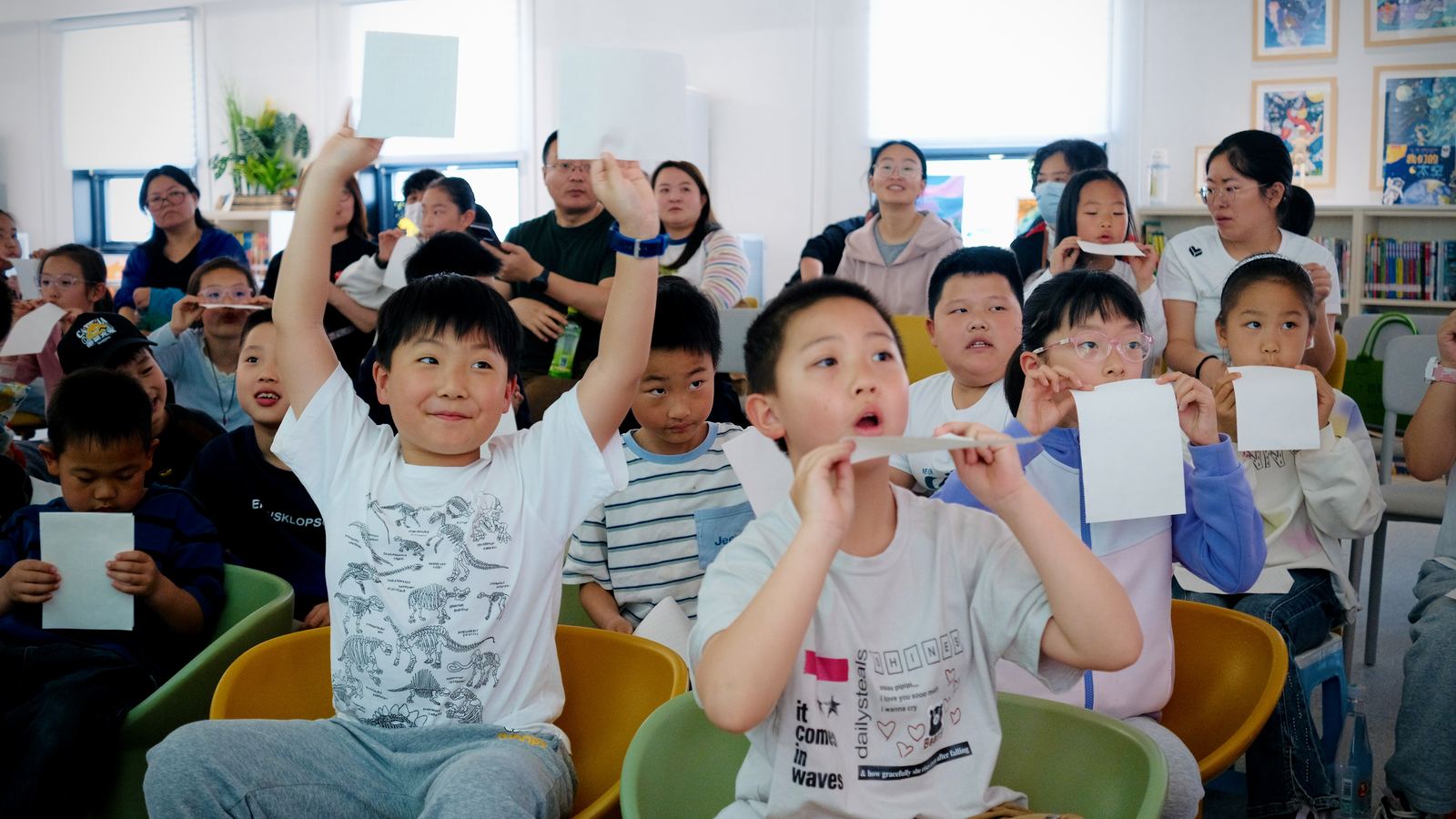 知间活动现场举卡互动的学生与家长